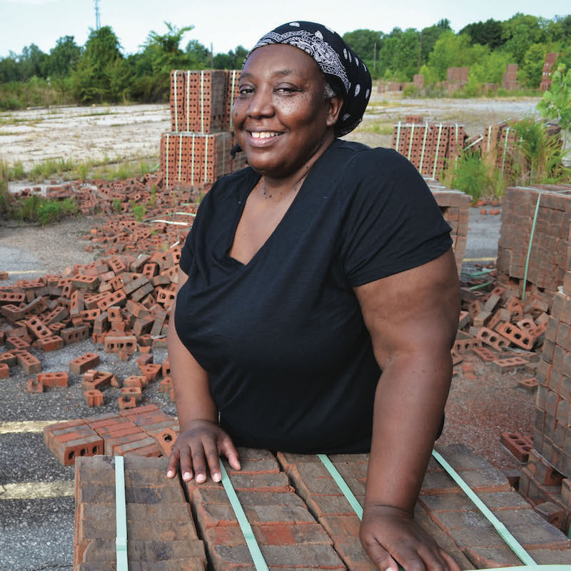 Donna Stephens standing in front of old piles of bricks.