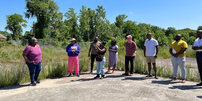 Donna Stephens speaking to eight community members standing outside on a blue-sky day at the Chattahoochee Brick site.