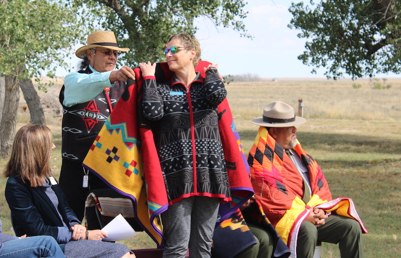 Christine Quinlan is honored with a traditional ceremonial blanket during a special event commemorating the expansion of the Sand Creek Massacre National Historic Site in October 2022