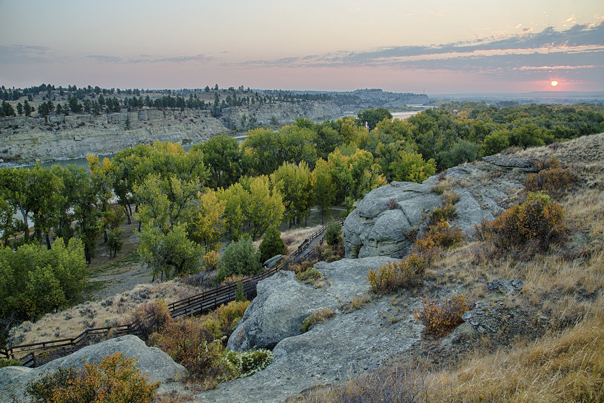 Rocky edge with fenced road and trees in the background