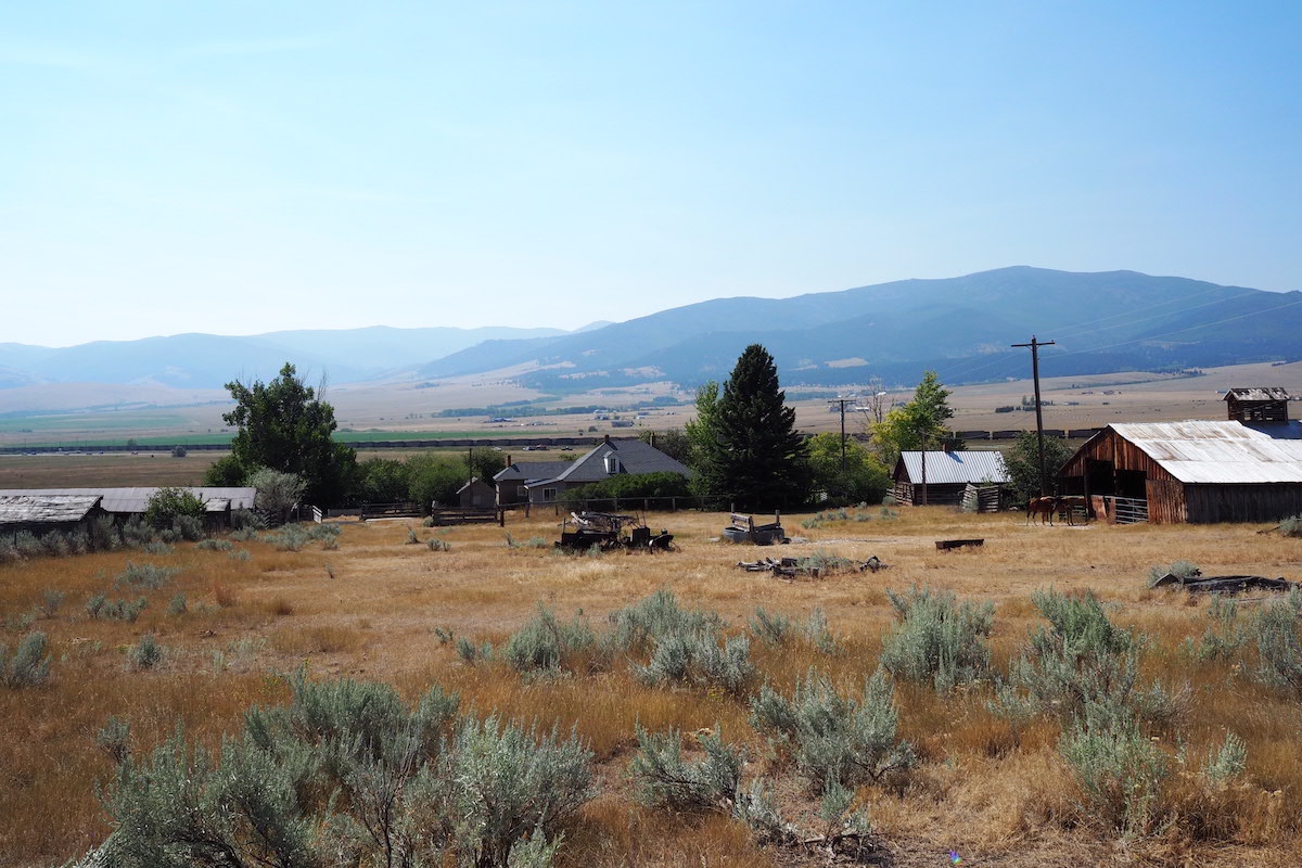 Farm buildings and horses on a ranch in a valley with mountains in the distance