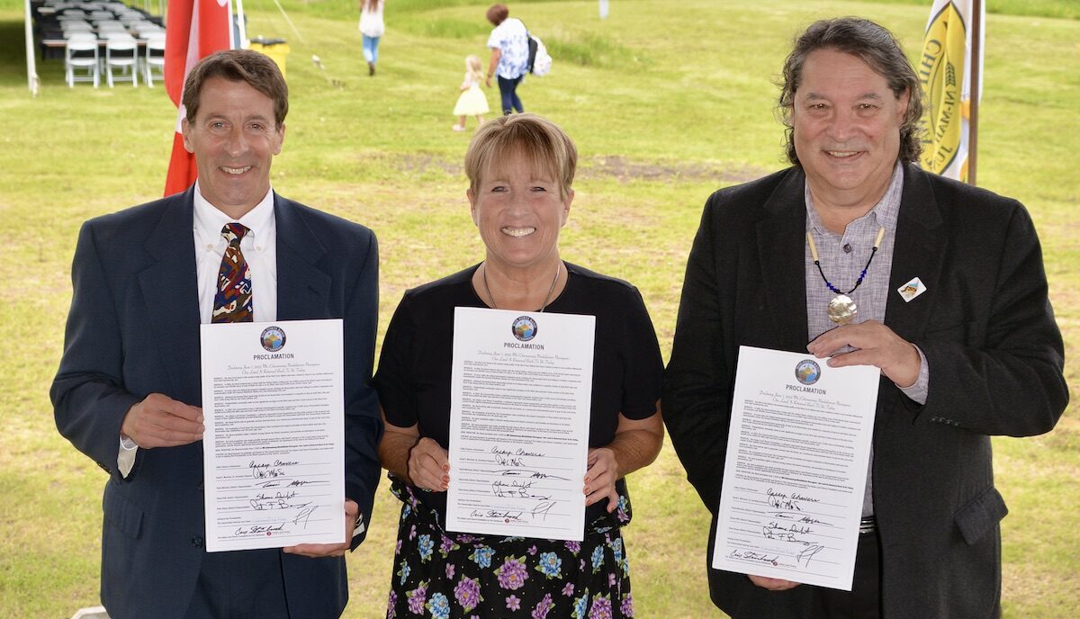 Three people holding signed proclamations and smiling