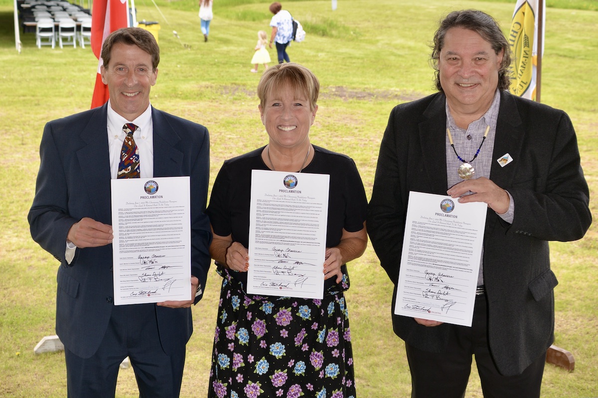 Three people holding signed proclamations and smiling