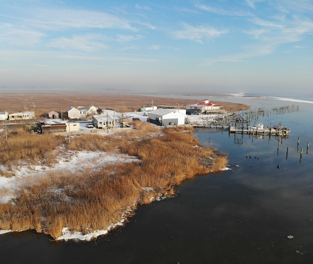 Houses and snowy grasslands on a waterfront