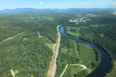 Road stretching through forested landscape with winding river on the right