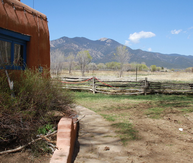 Stone house with wooden fence and mountains in the background