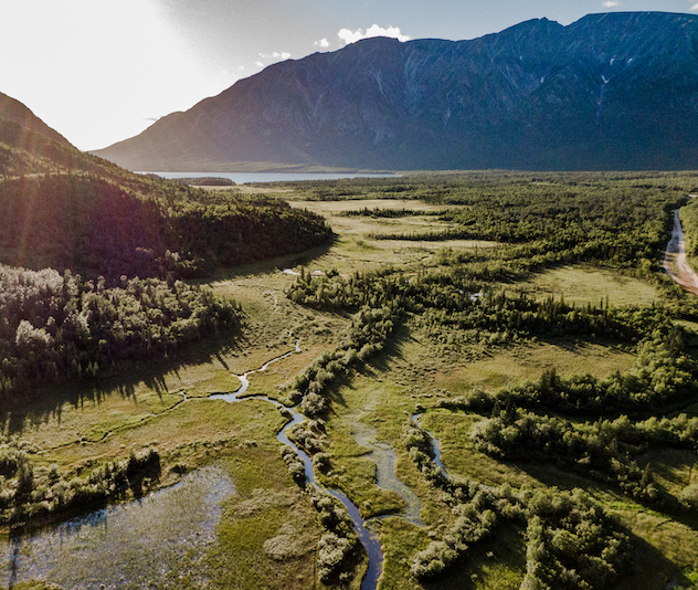 Trees and pond in a valley with mountains in the background