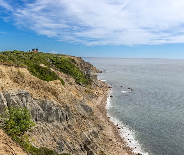 Cliffside along the ocean with a small lighthouse in the distance