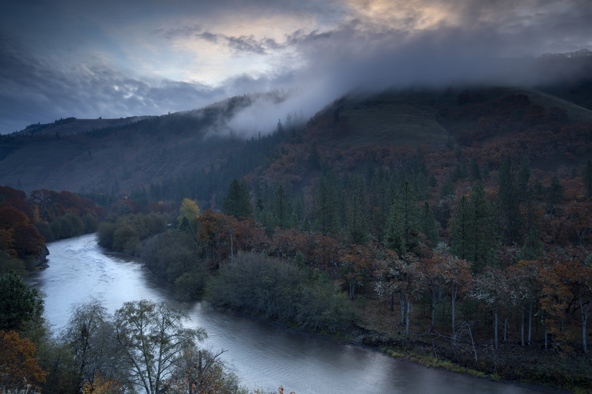 River and misty trees and mountain at dusk