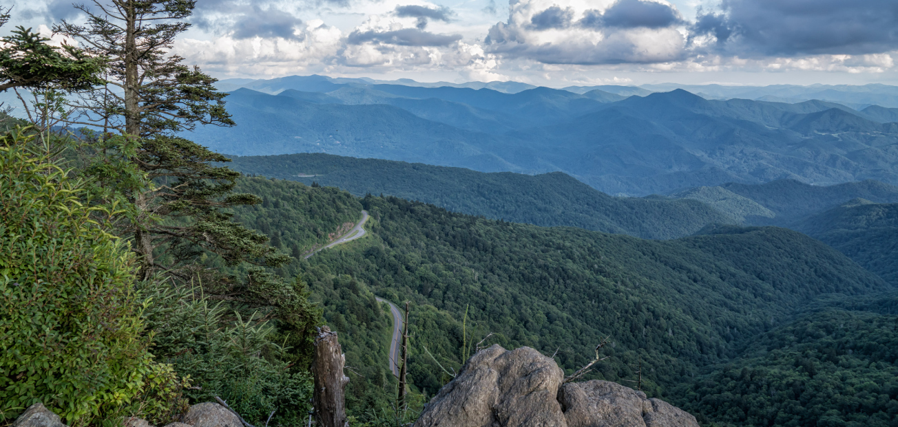 Scenic view of Balsam Gap from Waterrock Knob, showcasing majestic mountains from a rocky cliff perspective.